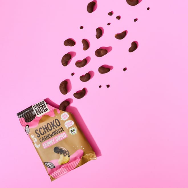 Naughty Nuts Schoko Cashewnüsse Skinny Dipped Packung mit Nüssen die herausfallen