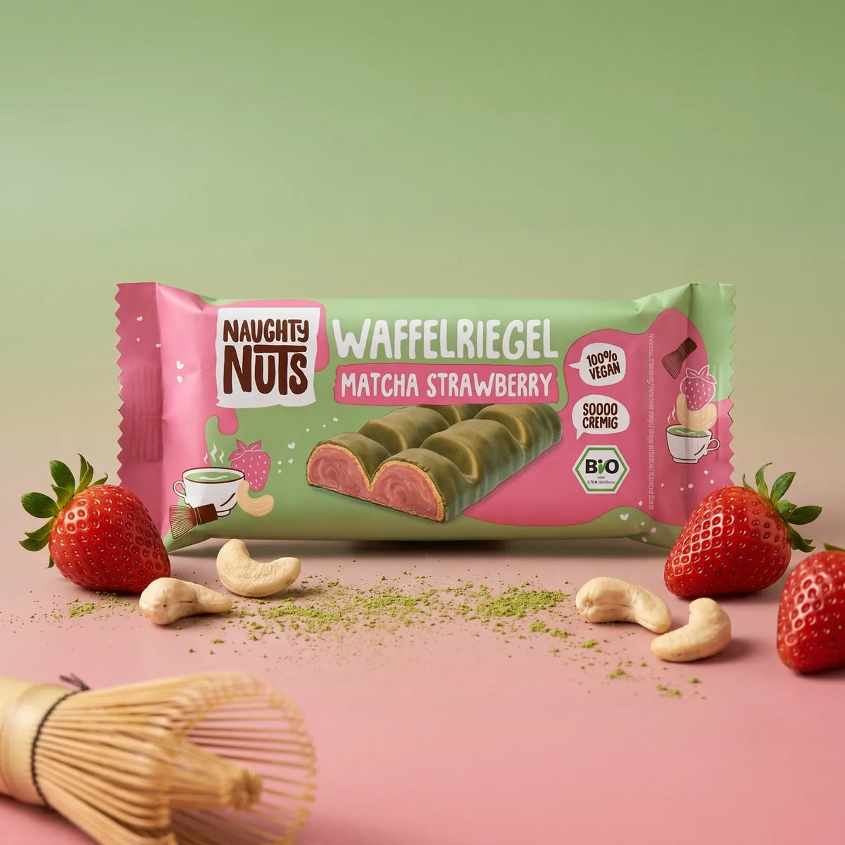Waffelriegel Matcha Strawberry mit Erdbeeren, Cashewkernen und Matcha-Pulver auf rosa und grünem Hintergrund