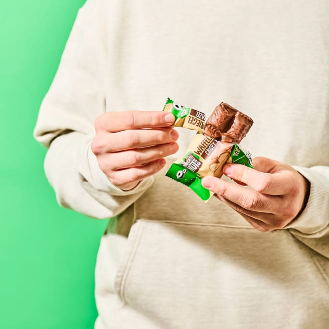 Hände halten zwei Bio Schoko-Waffelriegel in grüner und brauner Verpackung