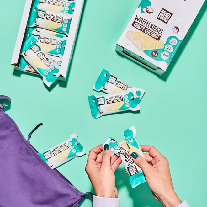 Bio Schoko-Waffelriegel Crispy Coconut in Verpackung, eine Hand öffnet einen Riegel