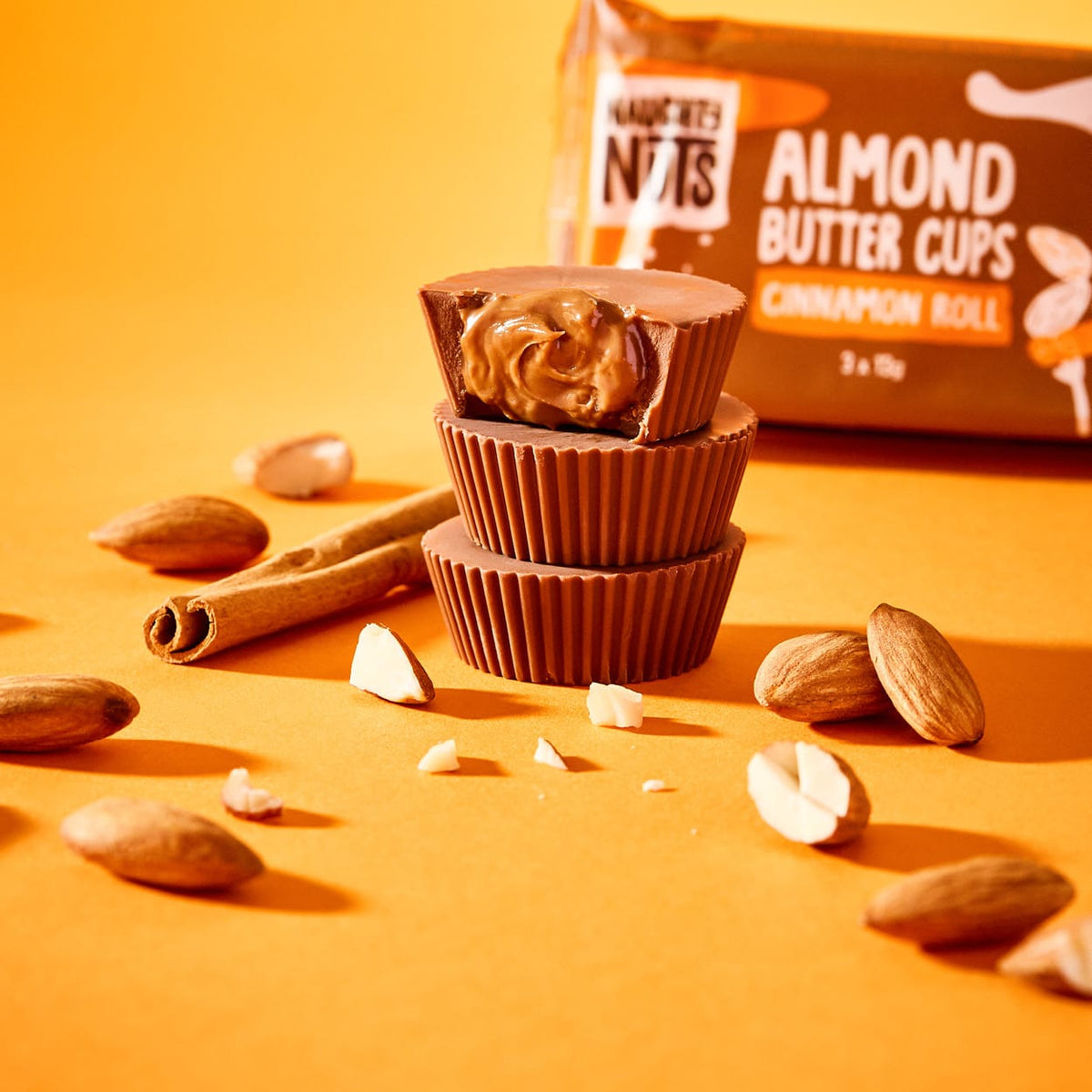 Bio Mandelbutter Cups Zimtschnecke, gestapelt, mit einem Biss und Mandeln und Zimtstangen