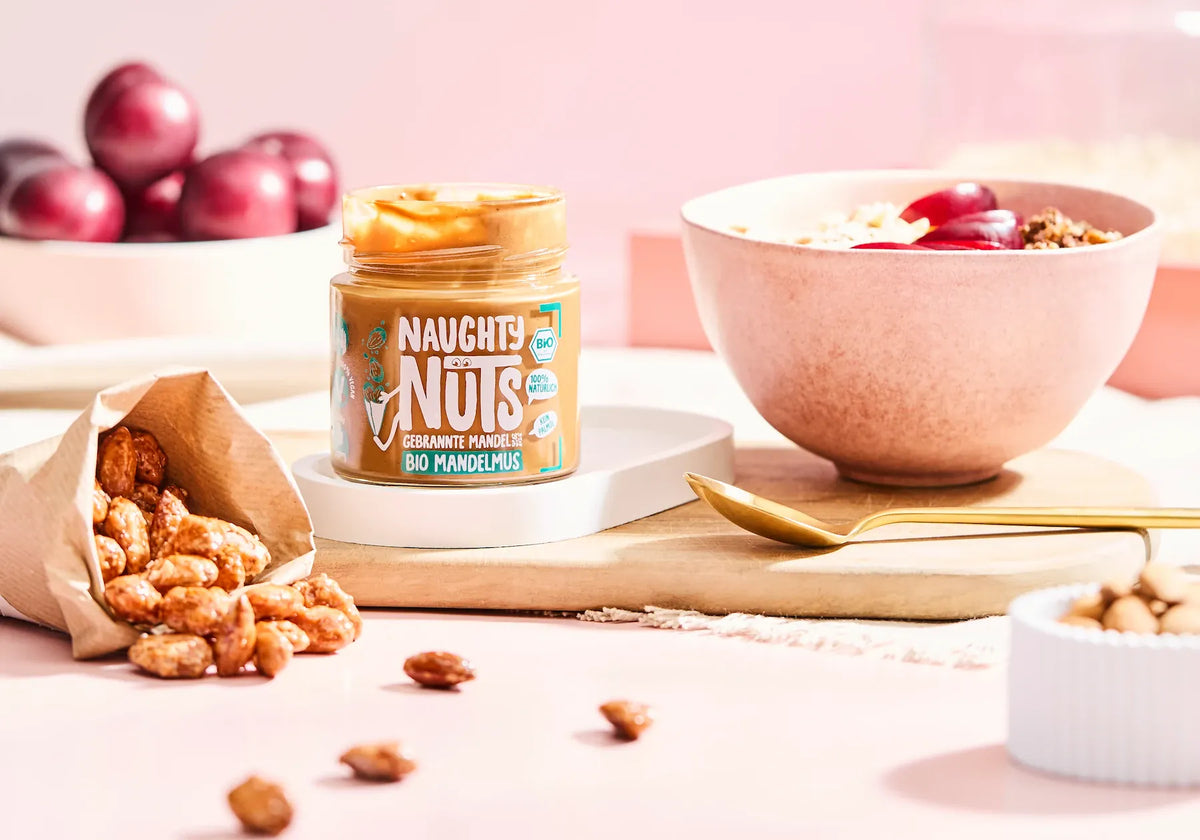 Naughty Nuts Bio Mandelmus, gebrannte Mandeln, Schale mit Müsli und Früchten, Tüte mit Mandeln