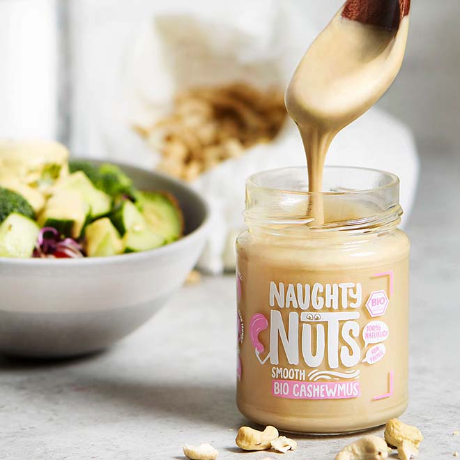 Naughty Nuts Smooth Bio Cashewmus wird mit einem Löffel aus dem Glas geschöpft