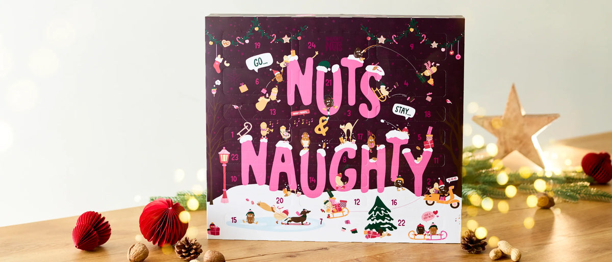 Nuts and Naughty Adventskalender mit weihnachtlichen Illustrationen auf einem Holztisch